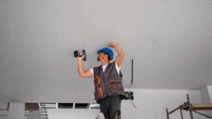 Profissional realizando a instalação de gesso acartonado em teto com parafusadeira, seguindo normas técnicas.