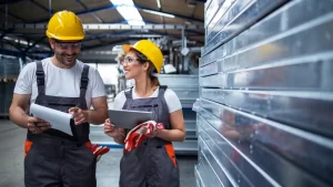 Profissionais da construção civil avaliando estrutura metálica para instalação de drywall em ambiente industrial.